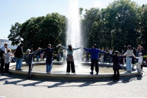 A group of people form a circle around a water fountain.